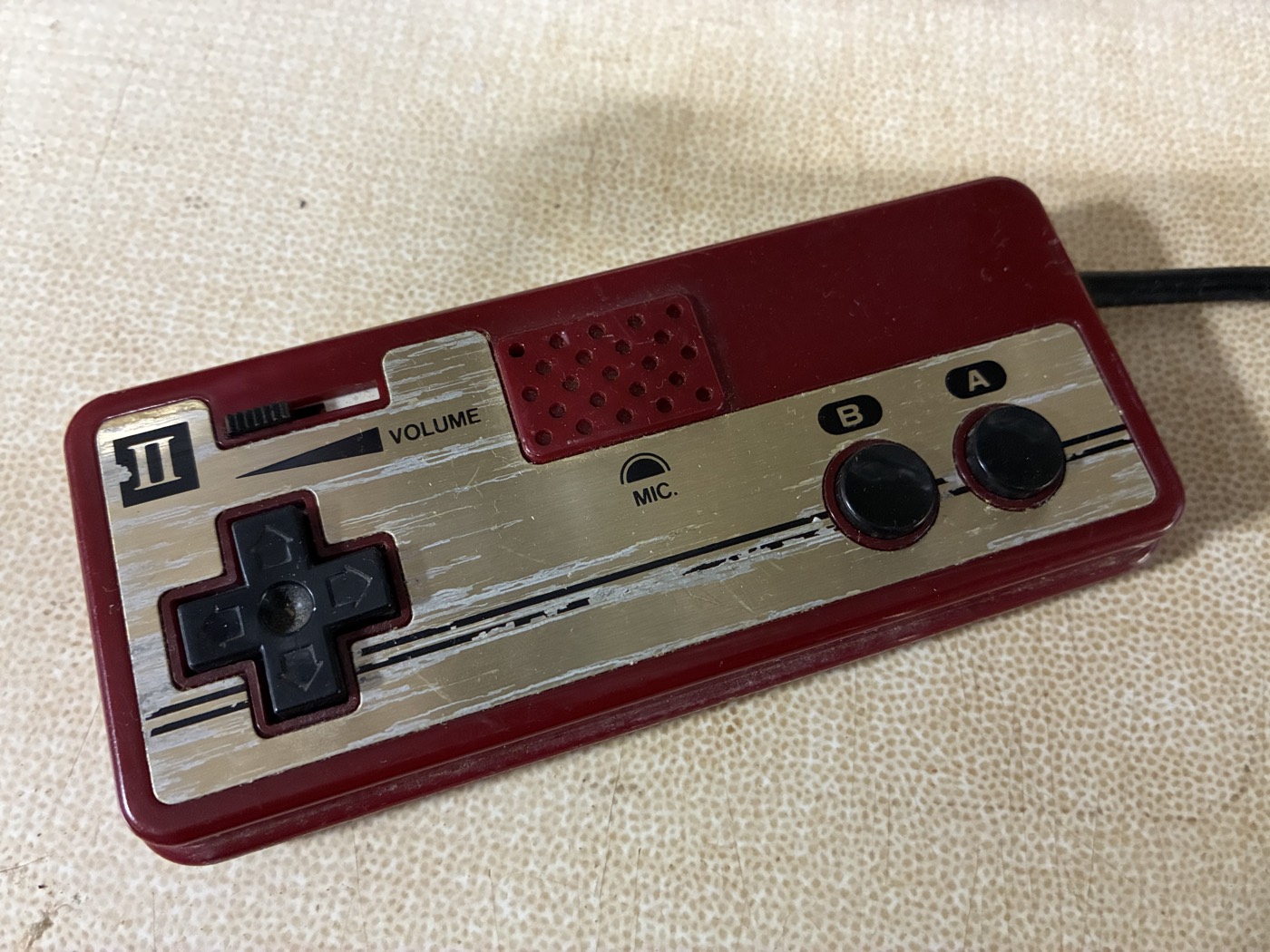 A Famicom Player-2 controller with its microphone grille and volume slider