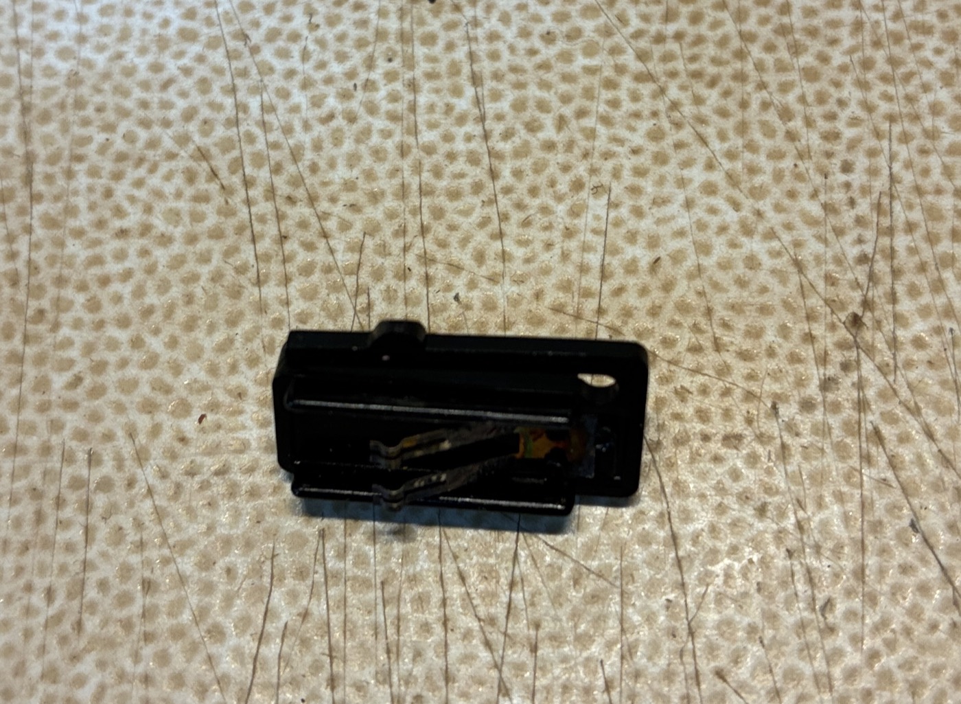 The volume slide switch removed, showing its small internal metal contacts